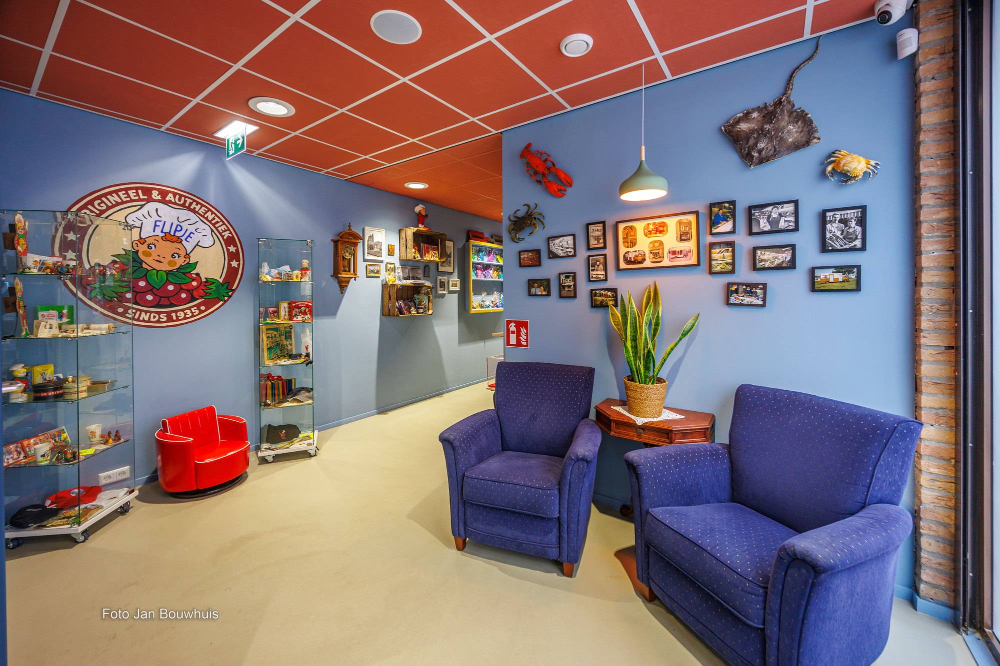 De zithoek van de kadowinkel: twee blauwe fauteuils, vitrines met streekproducten en het bord van Flipje aan de muur.