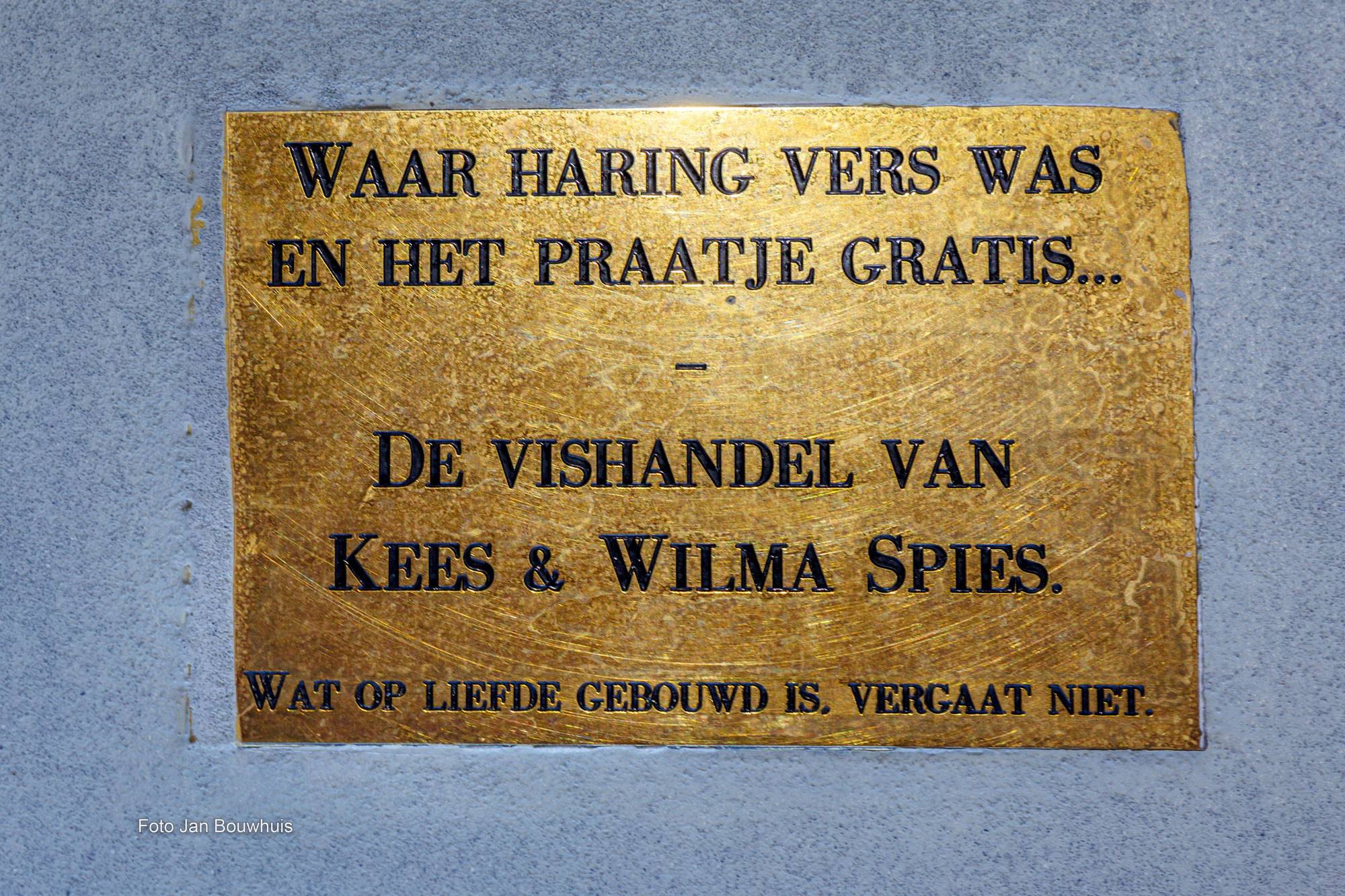 Koperen gedenkplaat met de tekst: Waar haring vers was en het praatje gratis. De vishandel van Kees & Wilma Spies. Wat op liefde gebouwd is, vergaat niet.